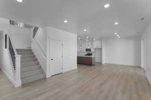 Unfurnished living room featuring recessed lighting, stairs, and light wood finished floors