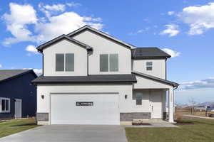 View of front of home with stucco siding, a garage, and driveway