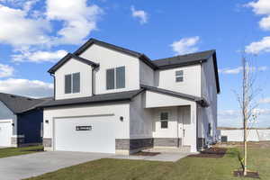 View of front facade with an attached garage, concrete driveway, stucco siding, and a front lawn