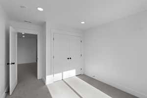 Unfurnished bedroom with recessed lighting, light colored carpet, and a closet