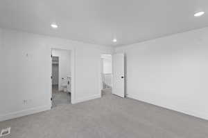 Unfurnished bedroom with recessed lighting, light colored carpet, and ensuite bath