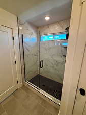Full bath with a marble finish shower and tile patterned floors