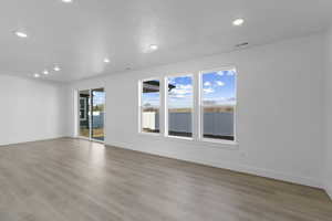 Unfurnished room with healthy amount of natural light, light wood finished floors, and recessed lighting