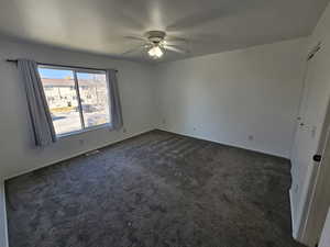 Room with dark colored carpet and ceiling fan