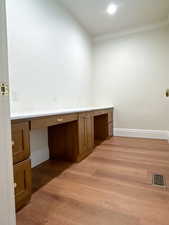 Unfurnished office with built in study area and light wood finished floors