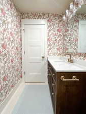 Bathroom with wallpapered walls, vanity, and light tile patterned floors