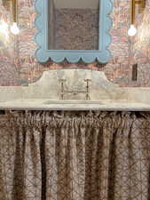 Bathroom featuring wallpapered walls and a sink