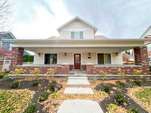 View of front of house with a porch, brick siding, and board and batten siding