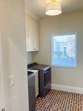 Laundry area with brick floors, cabinet space, and washing machine and dryer