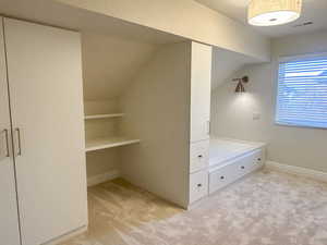 Spacious closet with light colored carpet and lofted ceiling