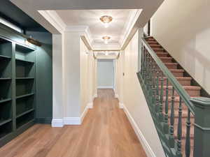 Corridor with ornamental molding, light wood-style floors, and a textured ceiling