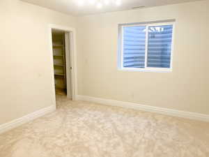 Unfurnished bedroom with a walk in closet and light carpet
