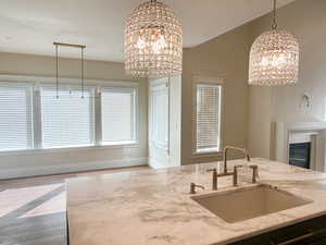 Kitchen featuring a chandelier, light stone countertops, pendant lighting, wood finished floors, and healthy amount of natural light