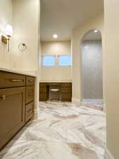 Full bath with light marble finish flooring, vanity, recessed lighting, and a walk in shower