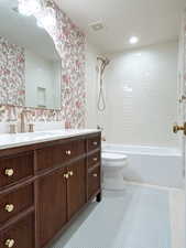 Full bath featuring vanity, wallpapered walls, and shower / tub combination