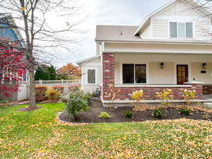 View of side of property featuring brick siding, board and batten siding, and covered porch