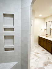 Full bath featuring vanity, light marble finish floors, and recessed lighting