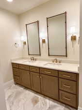 Bathroom featuring double vanity and light marble finish flooring