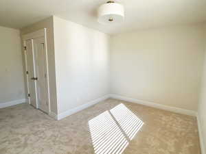 Empty room featuring baseboards and light carpet