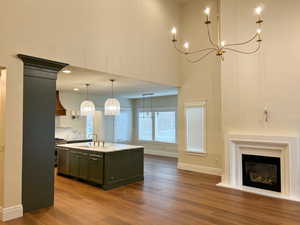 Kitchen featuring an island with sink, decorative light fixtures, a chandelier, light wood-style flooring, and open floor plan