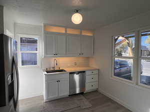 Kitchen featuring stainless steel appliances, white cabinetry, tasteful backsplash, dark wood finished floors, and ornamental molding