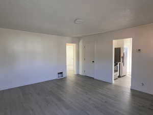Unfurnished room with dark wood-type flooring and a textured ceiling