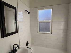 Full bath with shower / bathtub combination and a textured wall