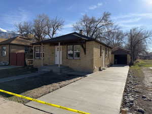 View of front of home with brick siding, a chimney, an outbuilding, and a detached garage
