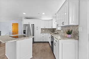 Kitchen featuring white cabinetry, light countertops, a kitchen island, stainless steel refrigerator with ice dispenser, and recessed lighting