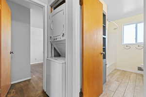 Laundry room featuring estacked washer and dryer and dark wood finished floors