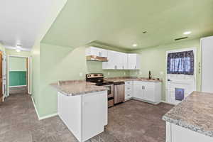 Kitchen featuring white cabinets, appliances with stainless steel finishes, light countertops, a peninsula, and under cabinet range hood