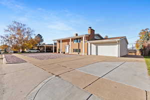 Split foyer home with concrete driveway, a chimney, and brick siding