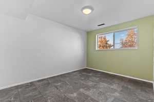 Spare room with baseboards and dark stone finish flooring