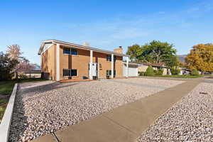Back of property with brick siding, a chimney, and driveway