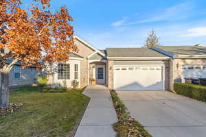 Ranch-style house with brick siding, roof with shingles, a front lawn, concrete driveway, and an attached garage