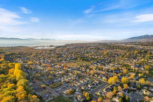 Aerial view of property and surrounding area featuring a mountain backdrop and nearby suburban area