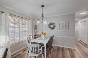Dining space with ornamental molding and wood finished floors
