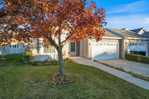 View of property hidden behind natural elements with concrete driveway, an attached garage, and brick siding