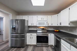 Kitchen with appliances with stainless steel finishes, white cabinetry, and dark countertops