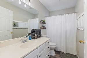 Full bath with curtained shower, vanity, and dark wood-style flooring