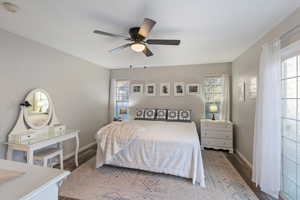 Bedroom featuring wood finished floors, multiple windows, and a ceiling fan