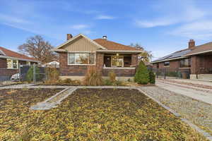 Bungalow-style house with a gate, board and batten siding, brick siding, and a chimney