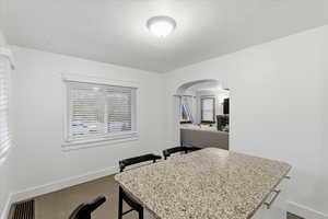 Dining area featuring arched walkways and dark tile patterned flooring