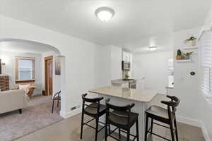 Kitchen featuring light tile patterned flooring, a breakfast bar, arched walkways, and appliances with stainless steel finishes