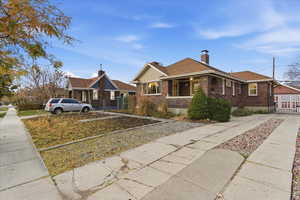 Bungalow-style house with brick siding, a chimney, a gate, board and batten siding, and a porch