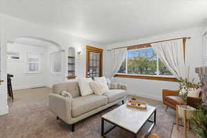 Carpeted living area featuring arched walkways and tile patterned floors