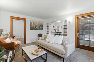 Carpeted living room featuring arched walkways and built in shelves