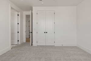 Unfurnished bedroom featuring light colored carpet and a closet