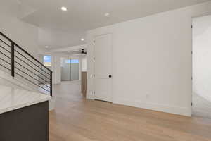 Empty room featuring recessed lighting, light wood-style flooring, stairs, and ceiling fan