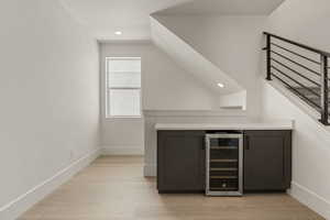 Bar area featuring beverage cooler, recessed lighting, light wood finished floors, stairway, and vaulted ceiling